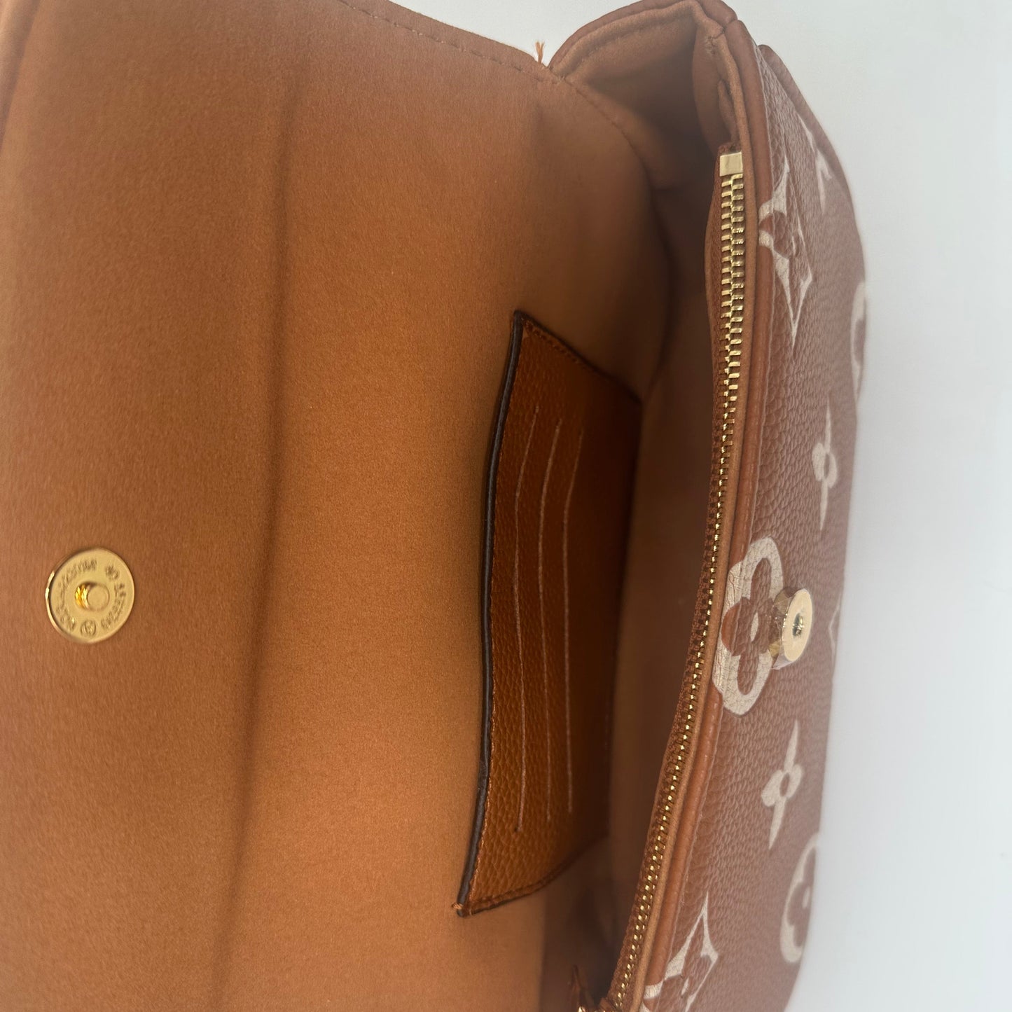 Brown handbag with gold zipper and logo on a white background