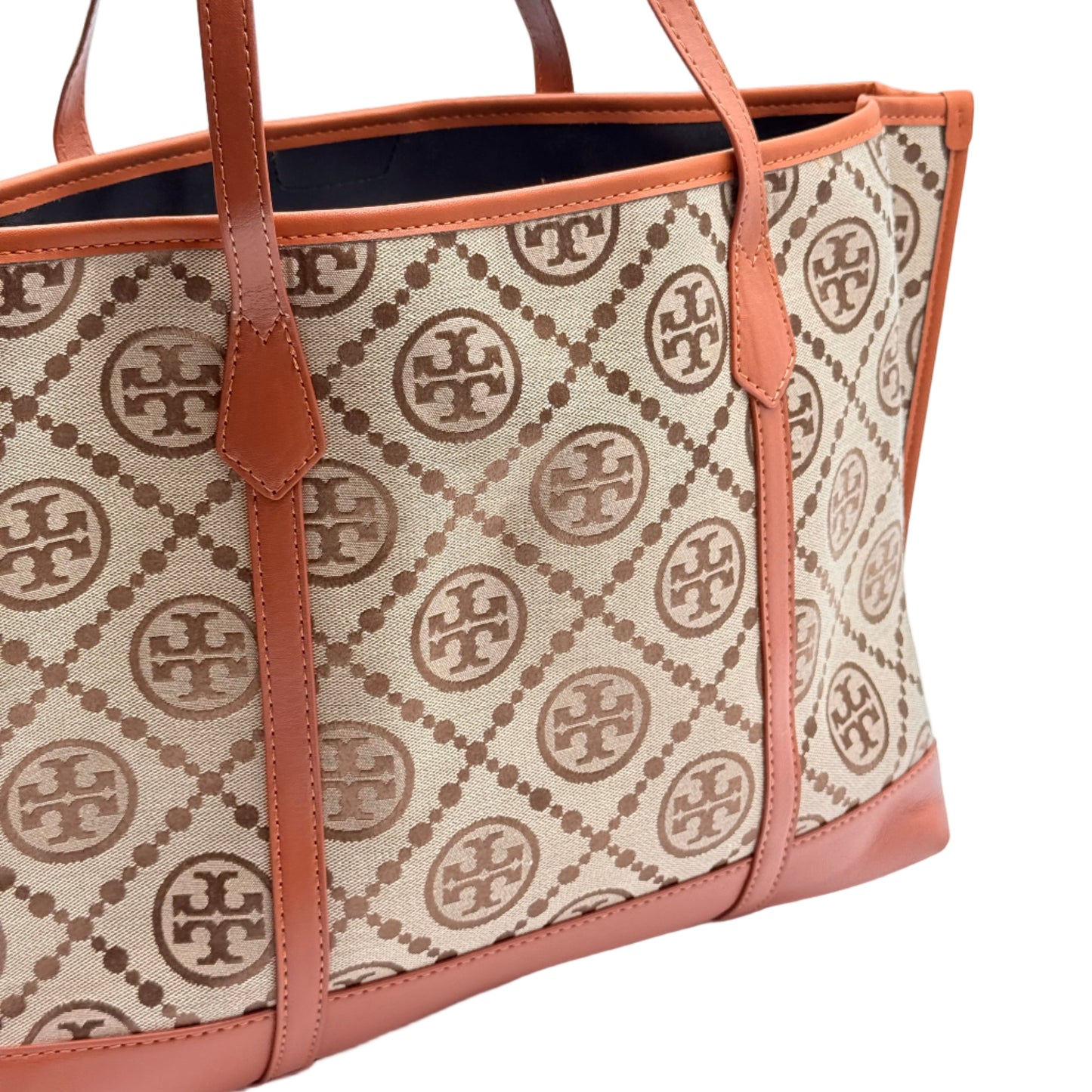 Designer handbag with brand logo pattern on beige fabric against a light blue background