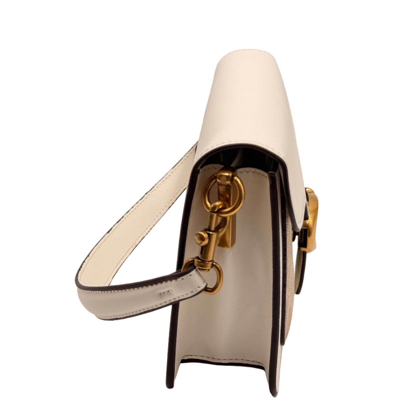 White and black high-heeled shoe with gold accents on a light gray background