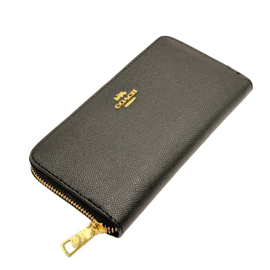 Black wallet with gold zipper on a beige background