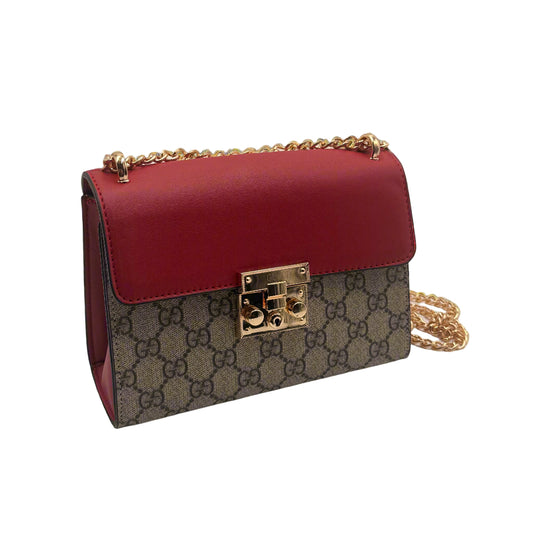 Designer handbag with red leather and patterned body on a light gray background