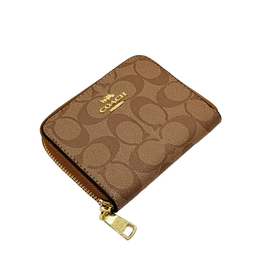 Coach wallet with gold zipper on a beige background