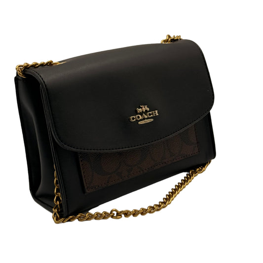 Black handbag with gold chain strap on a light gray background