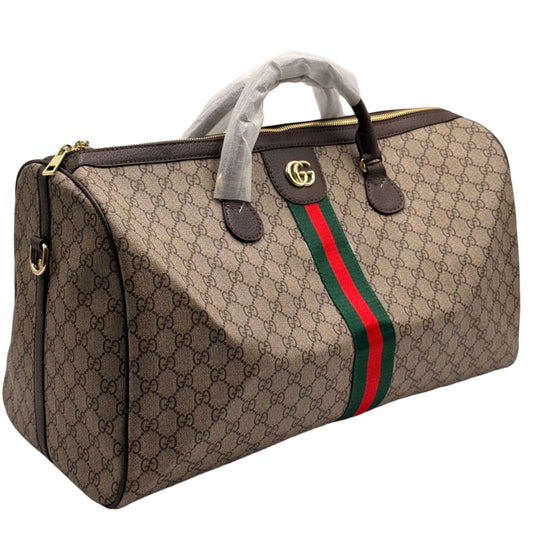 Gucci duffel bag with monogram pattern and red and green stripe on a light gray background
