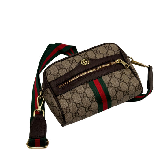 Gucci waist bag with monogram pattern and iconic green and red stripes on a light gray background